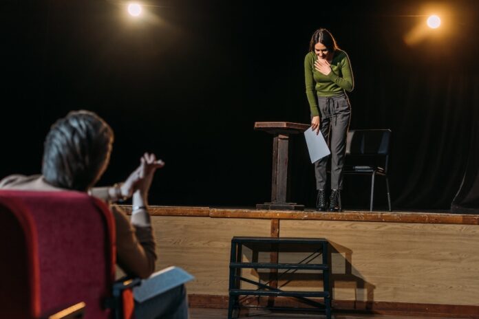 selective focus of theater director and bowing actress on stage